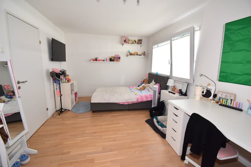 Bedroom with bed, desk, shelves, TV, mirror, and various decorative items.