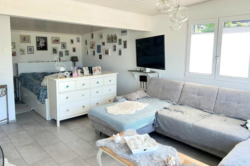 living room with a couch, a bed, a dresser, a TV, and a coffee table
