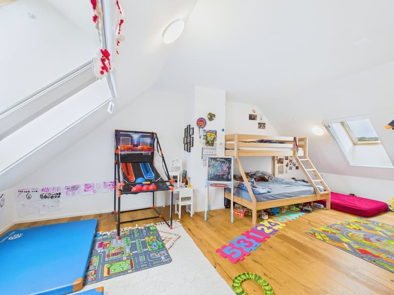 A children's room with wooden floor, white walls, bunk bed, game machine, desk, and toys