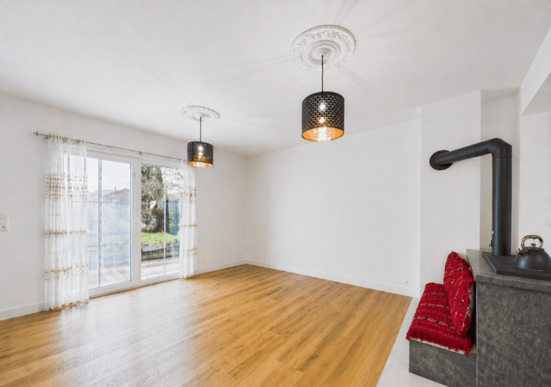 Empty room with wooden floor, white walls, sliding glass door, two lamps, fireplace