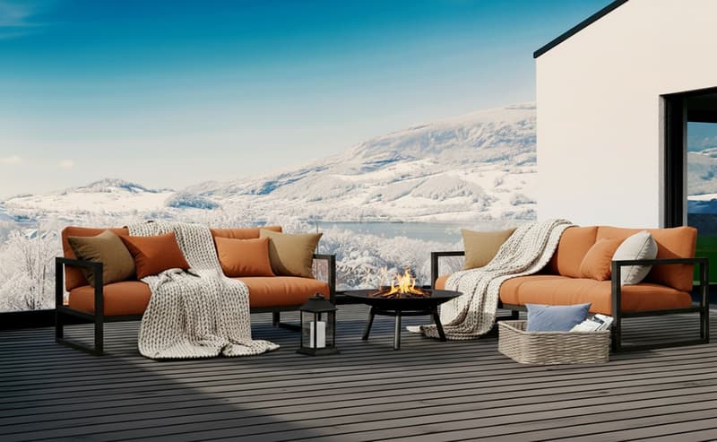 Modern outdoor living furniture with two orange sectional sofas, pillows, outdoor fire pit, table, wicker basket with candles and magazines