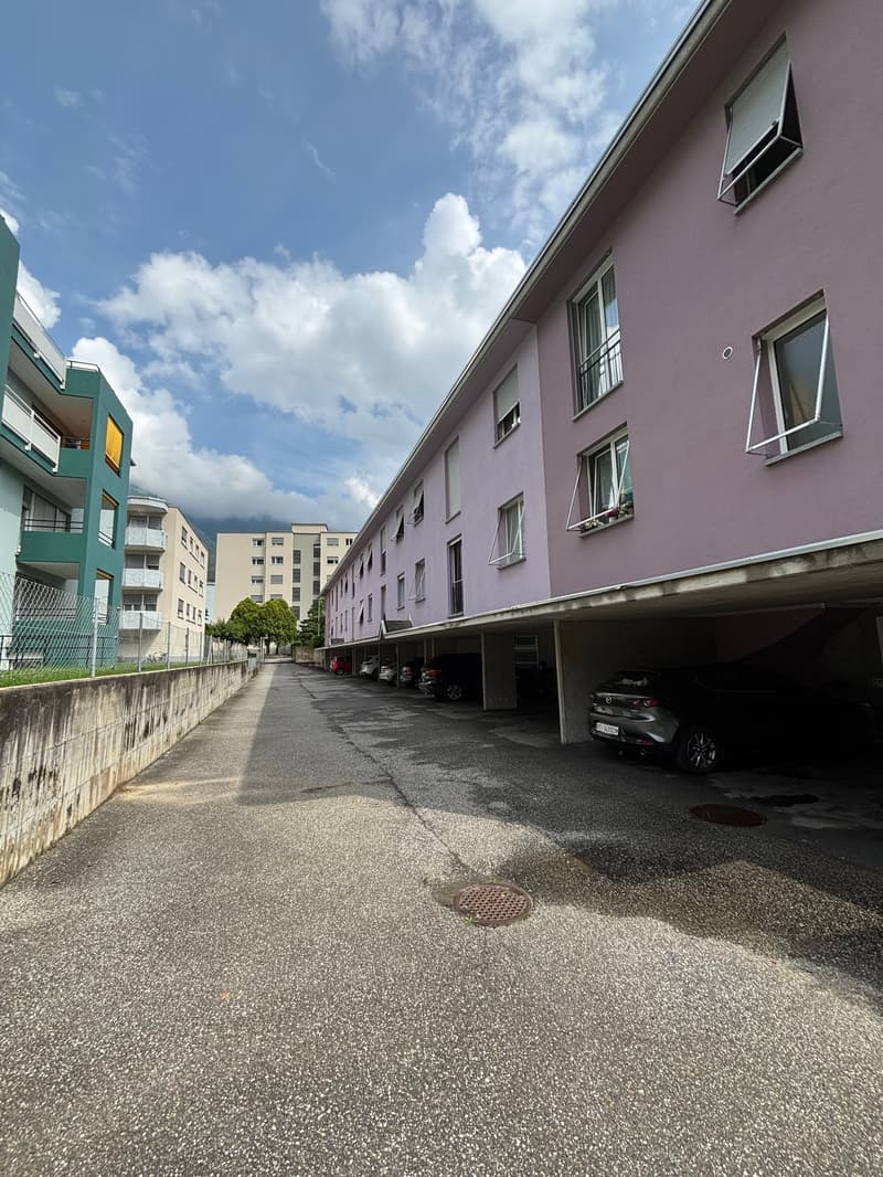 a row of apartment buildings, parking area underneath, concrete parking lot