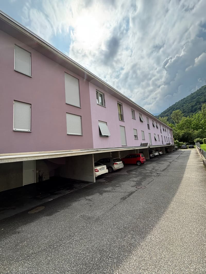 pink apartment building, basement level parking garage, road, cars