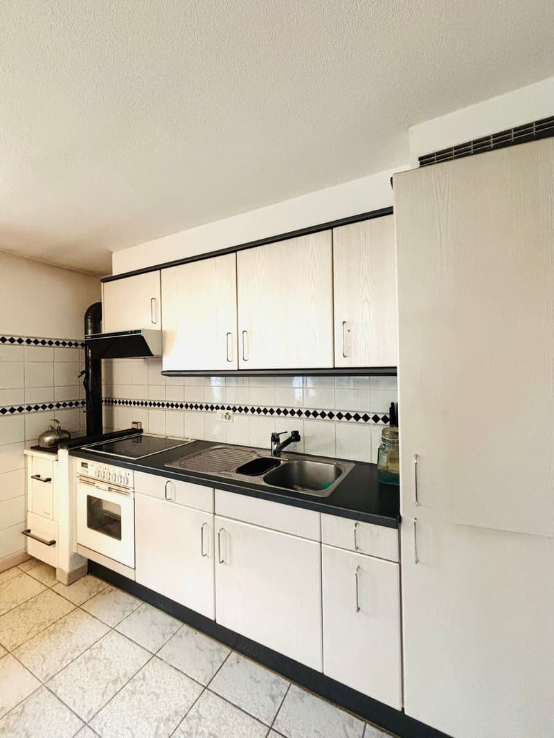 Kitchen: white cabinets, black countertop, stainless steel sink, faucet, electric oven, white tiled floor