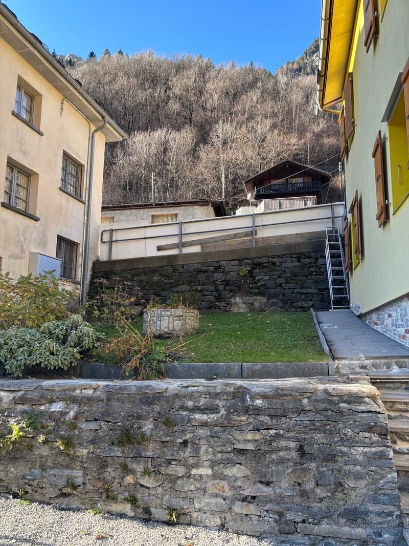 Exterior of an old building, stone walls, grass yard, mountain background
