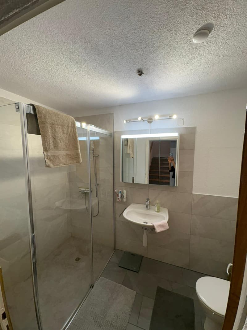 A modern and clean bathroom with a glass shower, sink, and toilet.