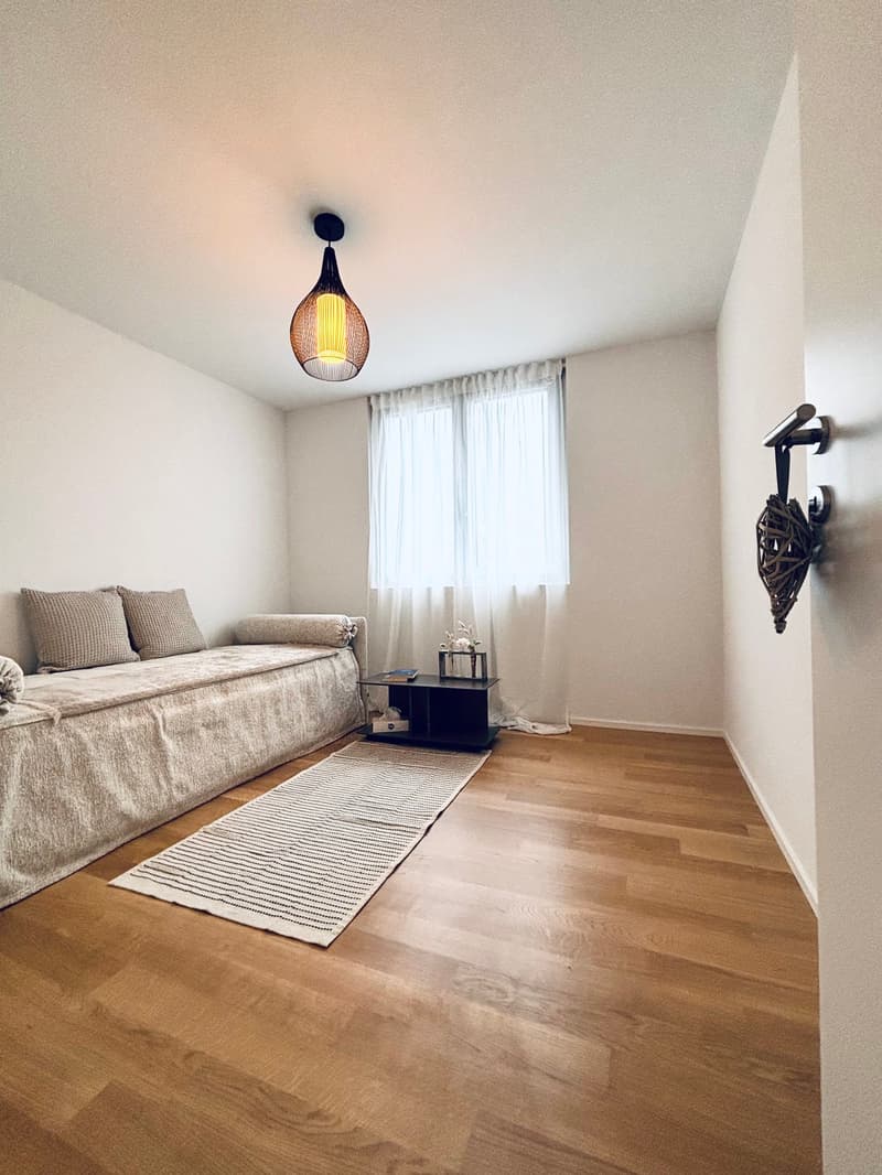 modern small room with white walls, wooden floor, couch, rug, side table, and a lamp
