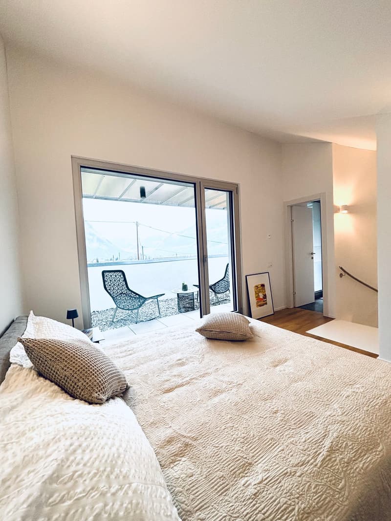 Large bed, two pillows, sliding glass doors to balcony, decorative picture frame