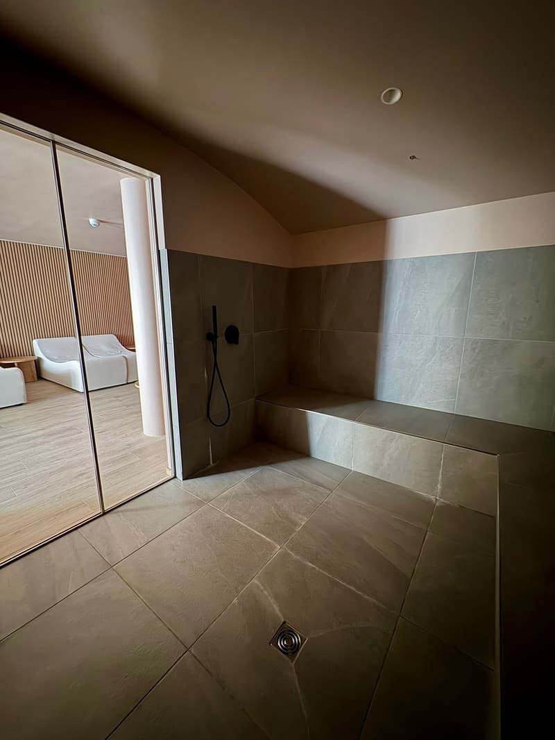 modern design shower area with tiled floors and walls, glass door, and lounge area with beds