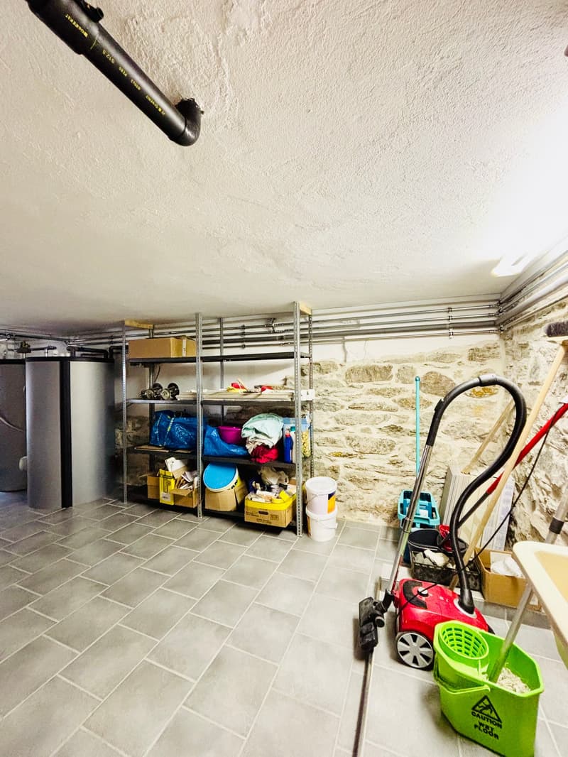 Storage room with tiled floor, metal shelves, storage boxes, buckets, cleaning equipment, water tanks, and a broom