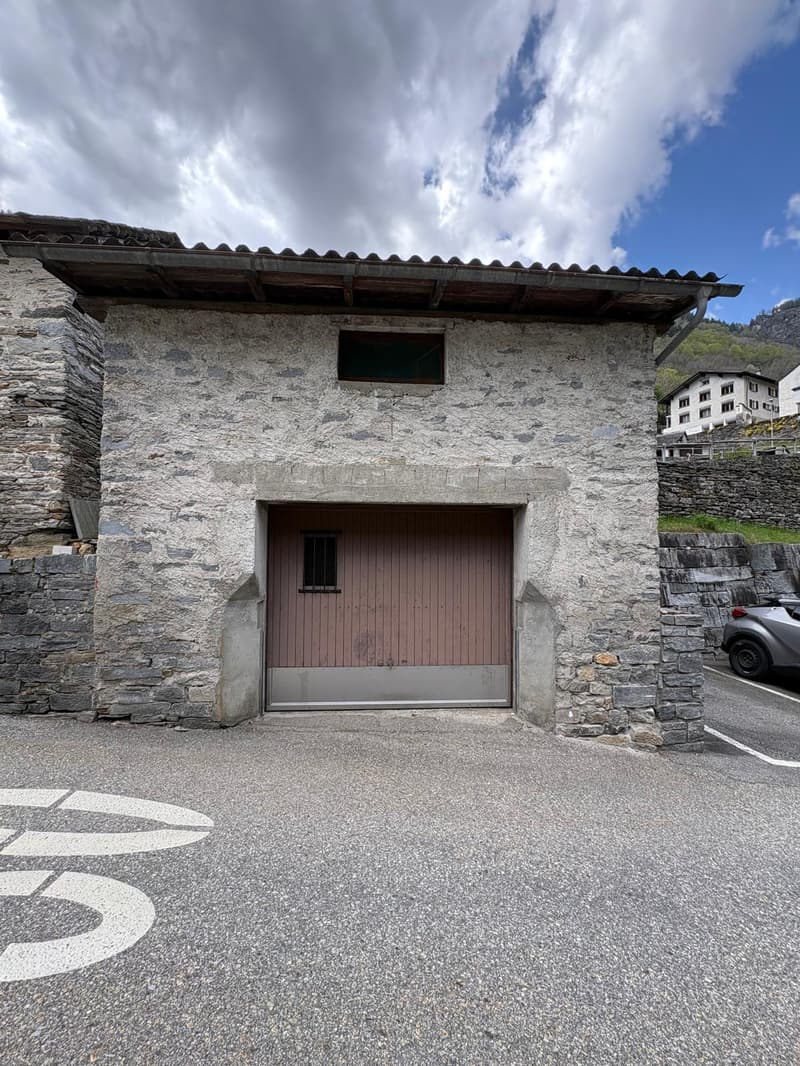 Stone building with a wooden garage door, stone walls, and a tiled roof