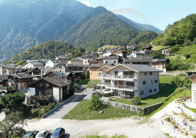 cluster of chalets with mountains in the background, several balconies visible