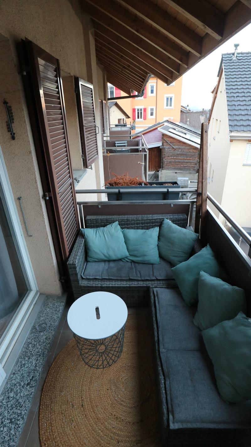 Balcony with sofa, table, rug, and plants