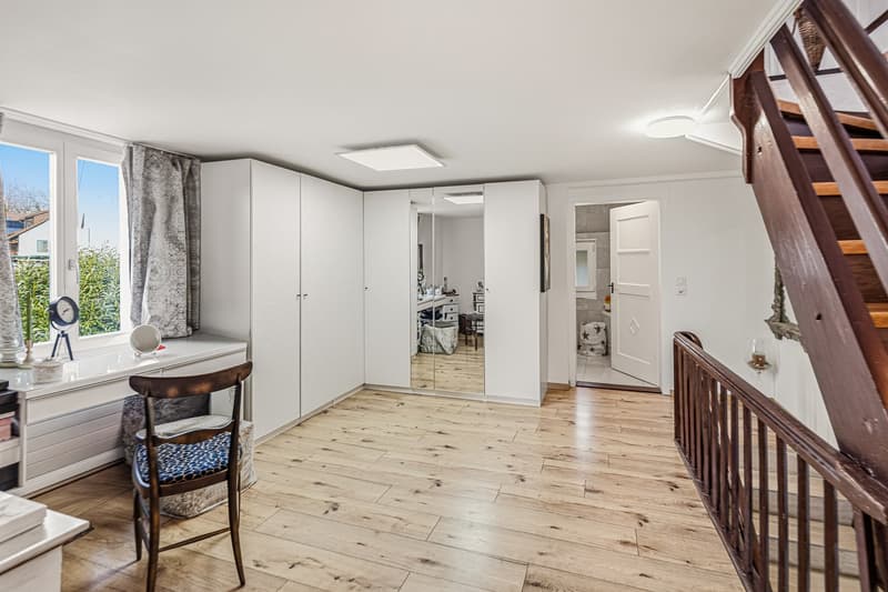 wooden floor, white walls, built-in wardrobes, mirror, window with curtains, wooden chair, desk with items
