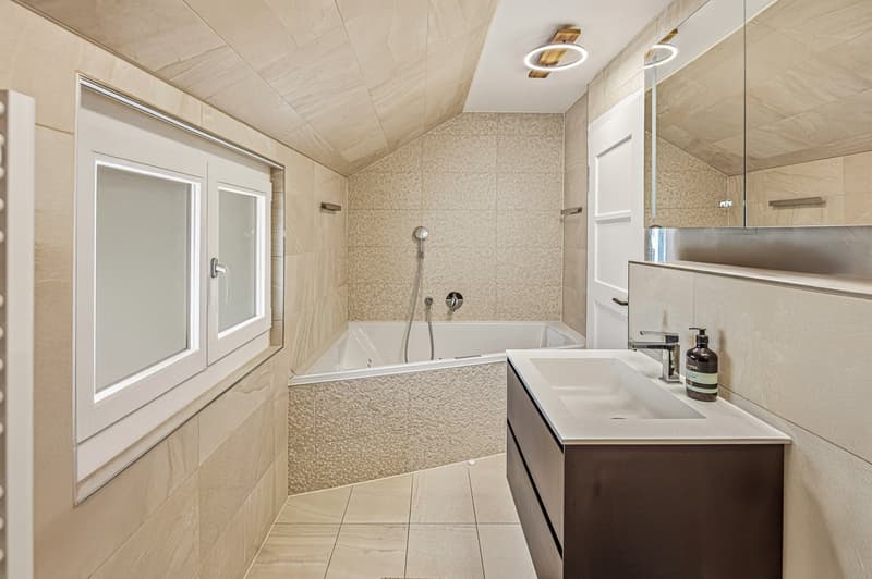 Bathroom with bathtub, shower, sink, mirror, and beige tiles