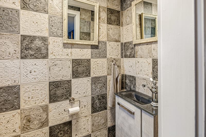 Bathroom with decorative tiles, sink, mirror, and towel rack