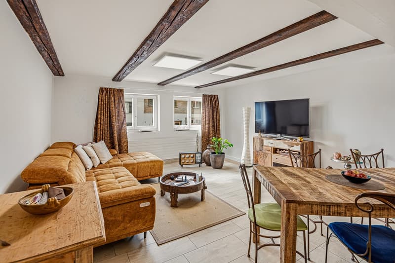 living room with sofa, coffee table, TV, dining table, chairs, rug, wooden beams, windows, potted plants