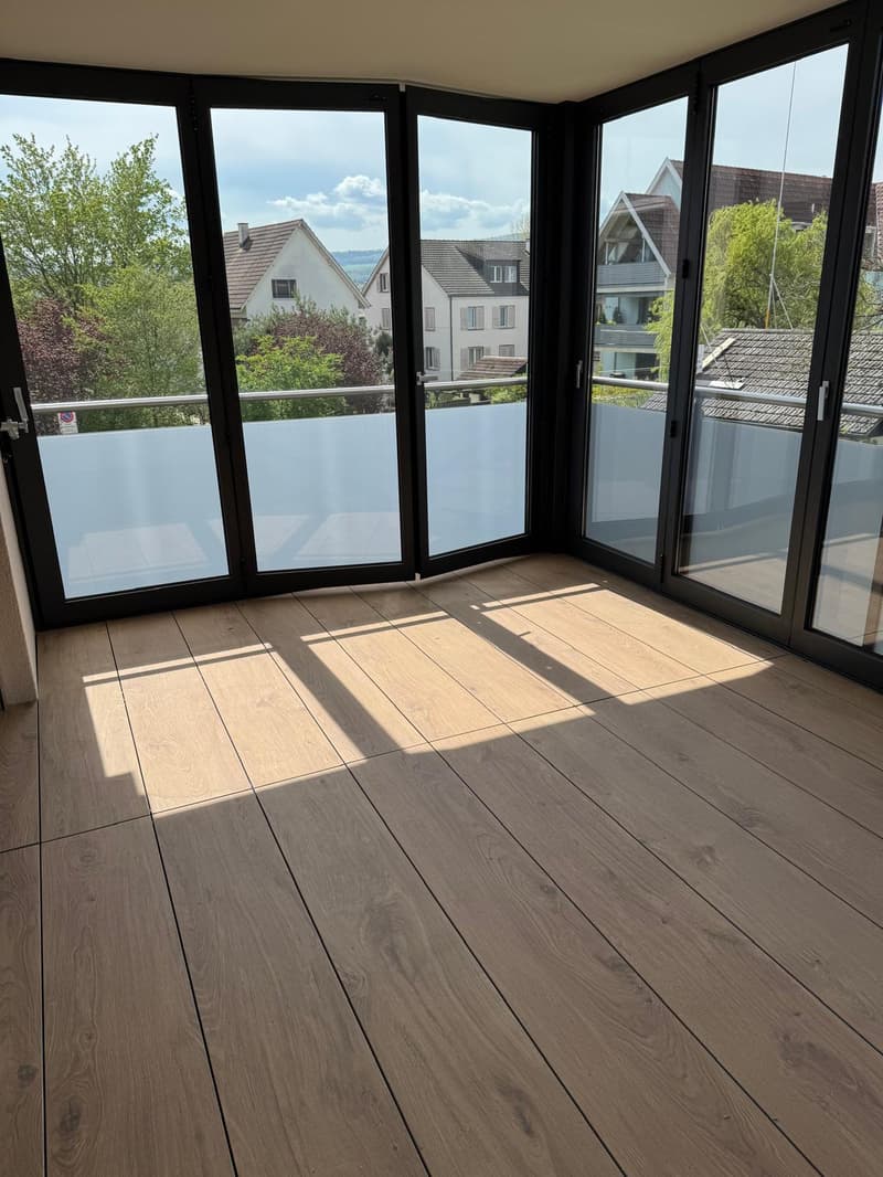 large windows, balcony, wooden floor, view of houses and trees