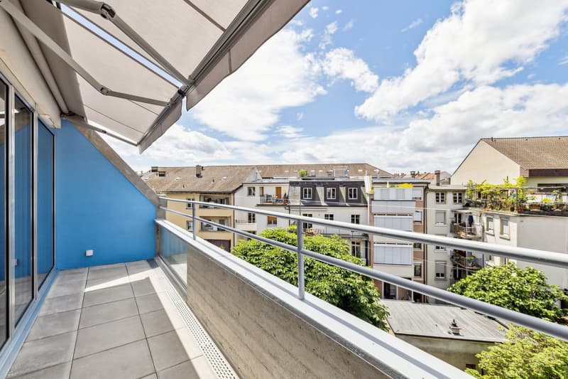 Balcony with metal railings, retractable awning, tiled floor, view of the city