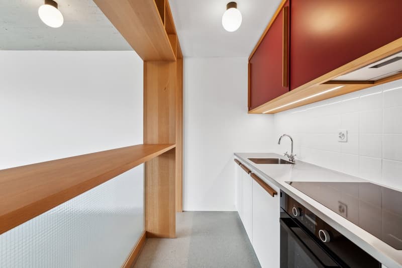 Modern kitchen with white cabinets, wooden countertops, and a dishwasher. The kitchen has a minimalist design with clean lines and a sleek appearance.
