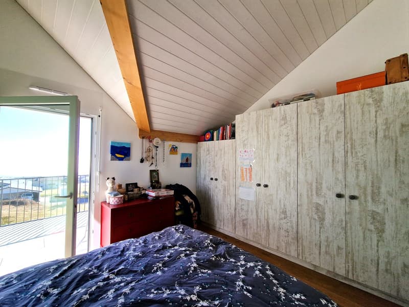 bedroom with bed, wooden wardrobe, red chest of drawers, balcony with railing, wooden ceiling