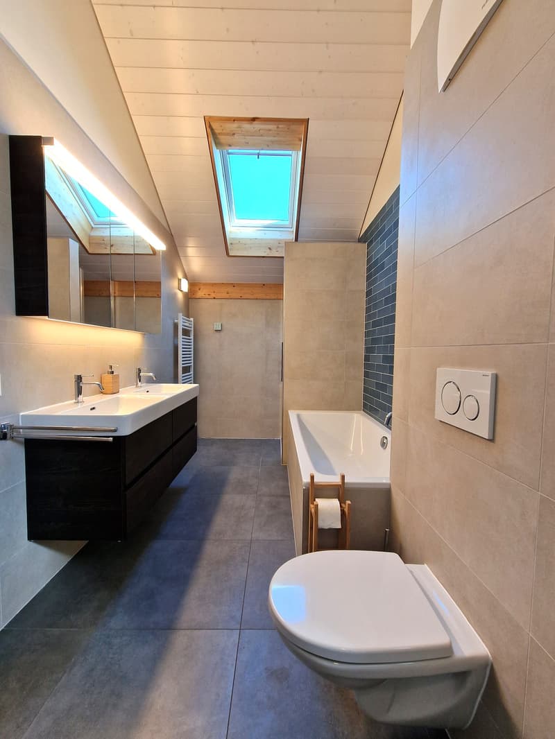 Bathroom with bathtub, sink, toilet, mirror, skylight, wooden floor, tiled walls, wooden toilet paper holder