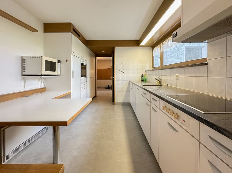 kitchen with white cabinets, white countertop, white table, microwave, stove, oven, sink, faucet, built-in drawers, windows, power outlet, tiled flooring, ceiling light