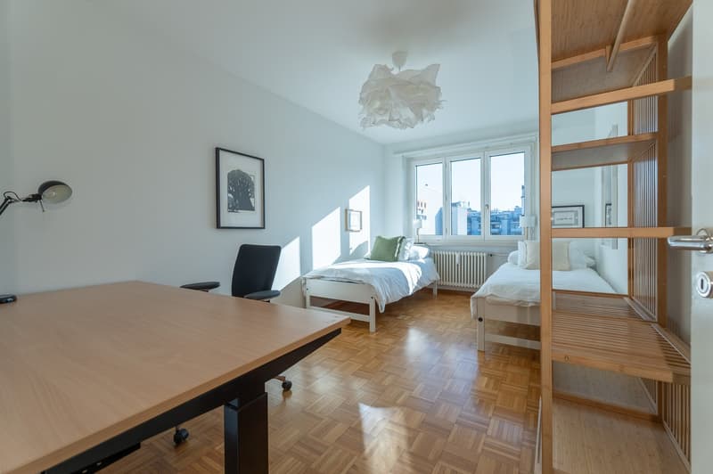 desk, two beds, white walls, wooden floors, radiators, chairs, bookcase, picture frames
