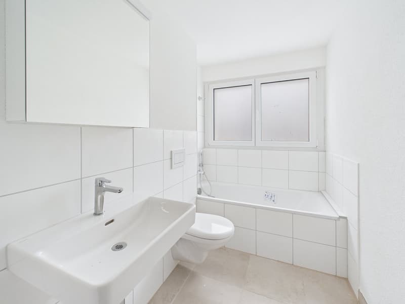 modern bathroom, white tiled walls, white ceramic sink, white toilet, bathtub with shower, no window