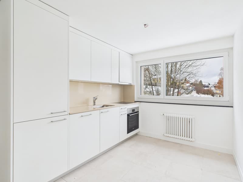 modern kitchen with white cabinets, tile flooring, sink, oven, radiator, large window