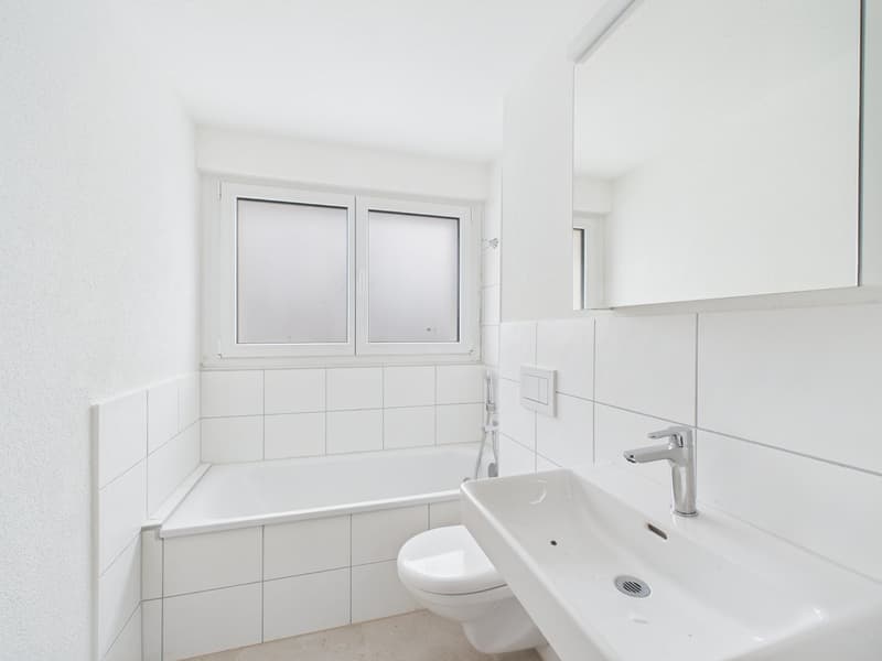 Bathroom with white walls, bathtub, toilet, sink, mirror, and faucet