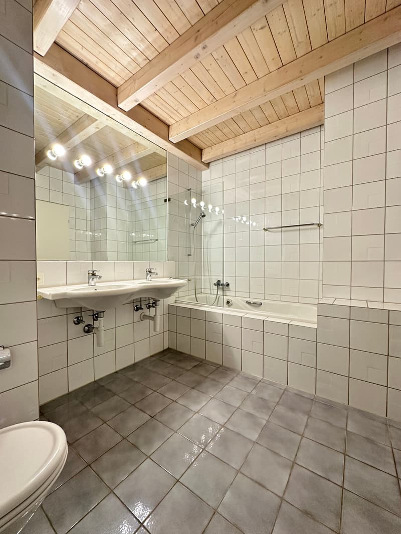white tiled walls, wooden ceiling, double sink, bathtub, shower, toilet