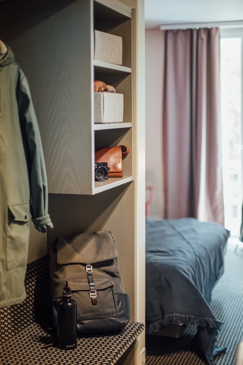 Wardrobe with shelves, handbag, jacket, camera, bed with dark grey sheet