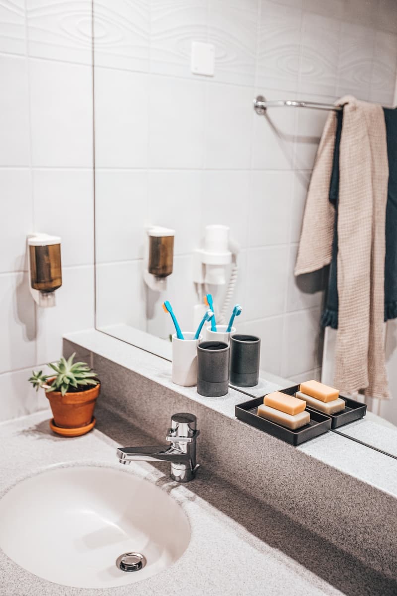Bathroom sink with soap and toothbrushes in cups on the counter