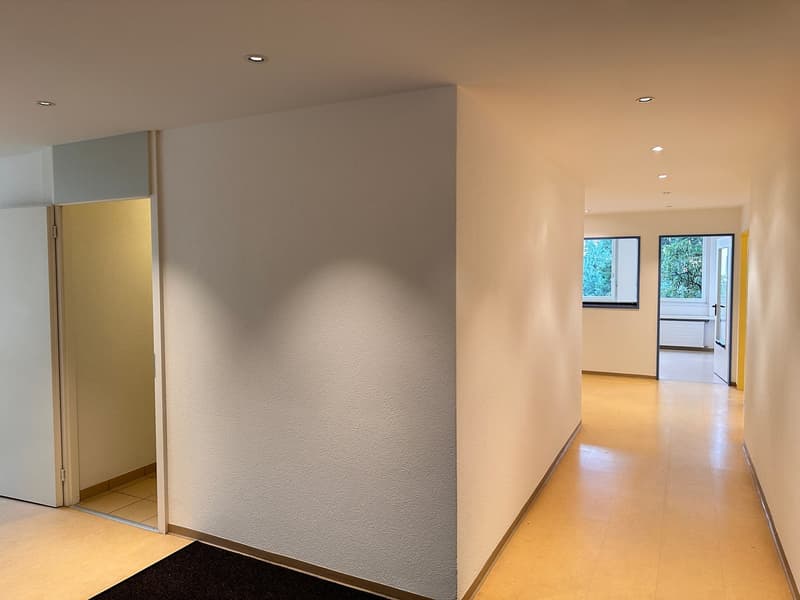 empty corridor with tiled floor, white walls, ceiling lights, and two doors on each side