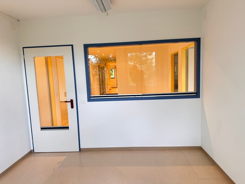 Empty room with white walls, wooden floor, a door and a large window with blue borders