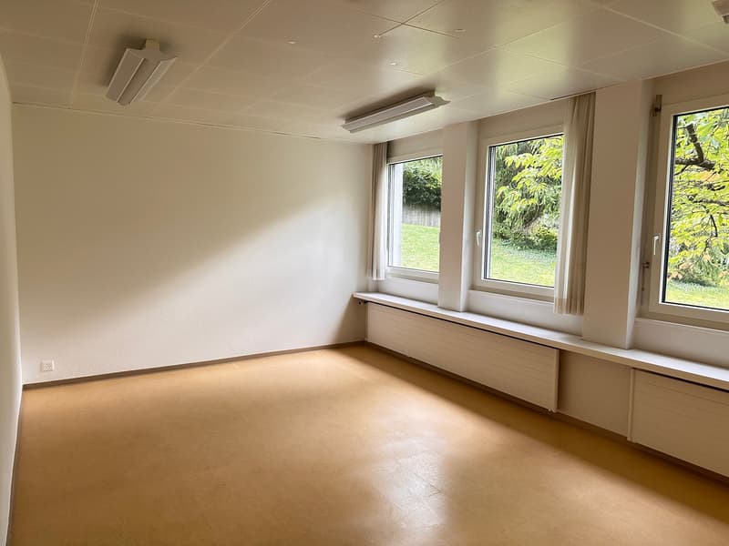 empty room with three windows, wooden floor, white walls, window seats, wall-mounted radiators