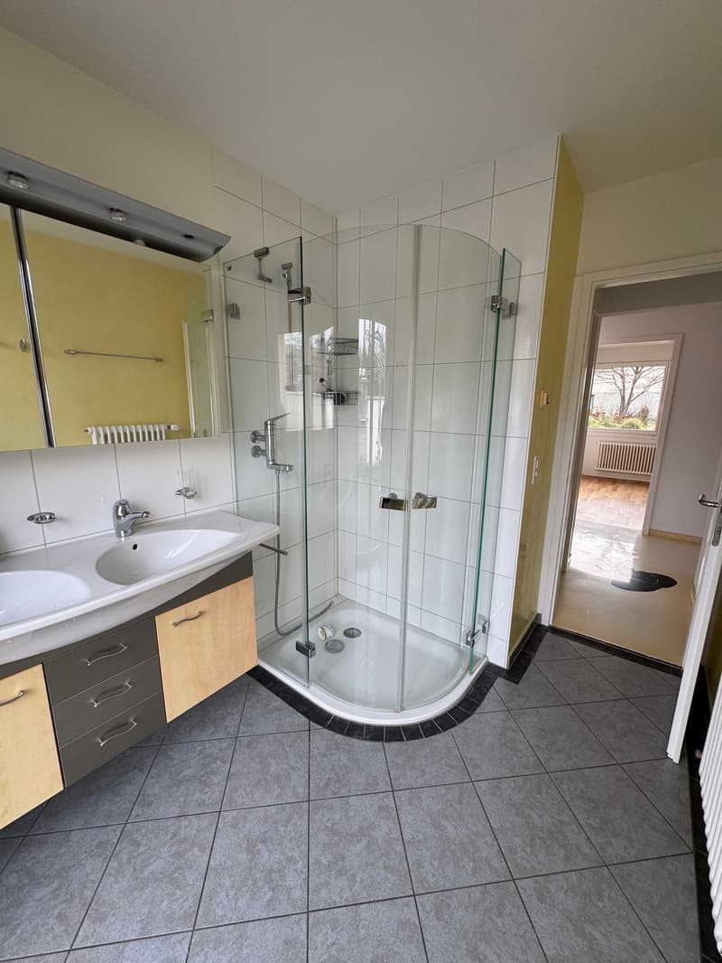 tiled floor, double sinks, separate shower with glass door, yellow cabinets, mirror, radiator