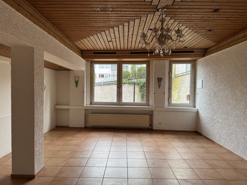empty room, brown tiles, wooden ceiling, three windows, radiator, chandelier