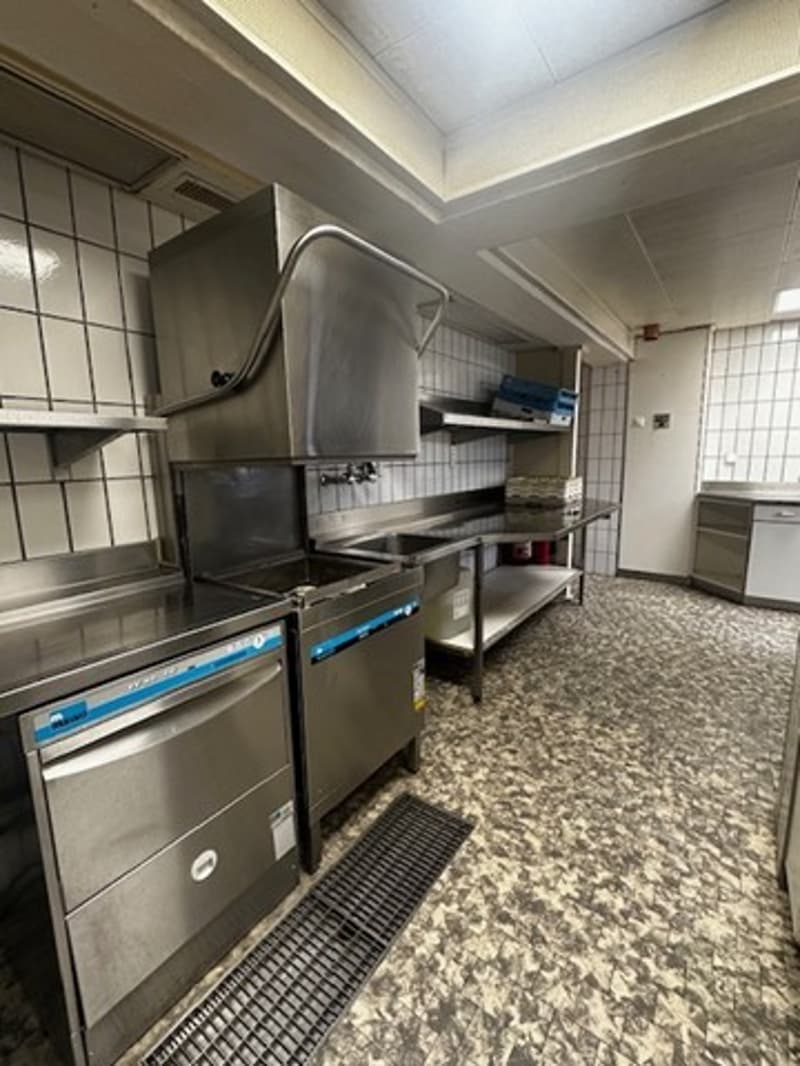 Commercial kitchen with stainless steel appliances, tiled walls, and countertops.