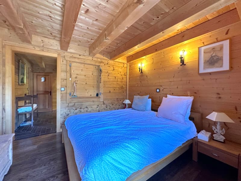 wooden walls, bed with blue sheets, bedside tables, lamps, picture frame, wooden door, small window