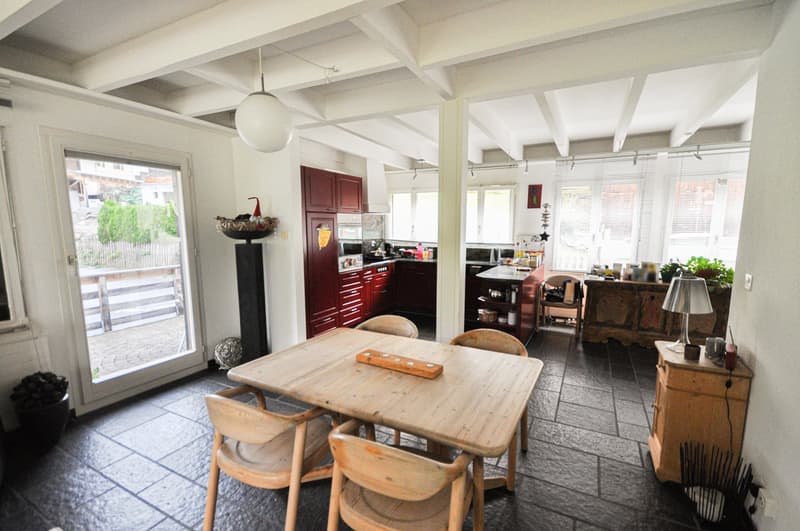 dining area with wooden table, wooden chairs, open kitchen, sliding glass door to outside, large windows