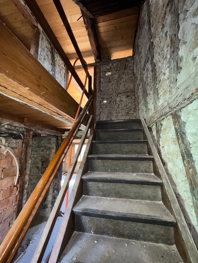 interior staircase, stone walls, wooden handrail, concrete steps, under renovation