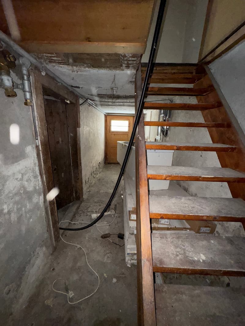 A concrete wall, wooden stairs, and a wooden door.