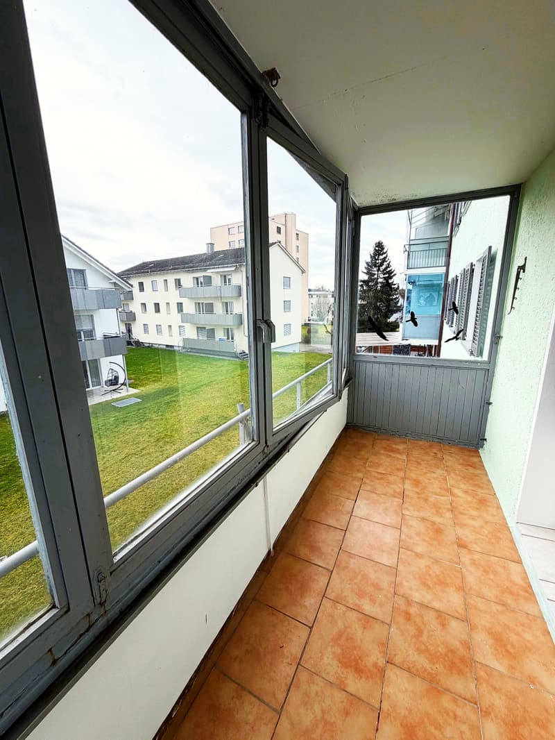 large windows, balcony, tiled floor, view of a grassy field and buildings