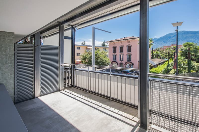 Balcony with metal railings, tiled floor, view of the street and mountains