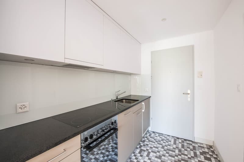 modern kitchen with white cabinets, black countertops, integrated oven and dishwasher, stainless steel sink, faucet, power outlet