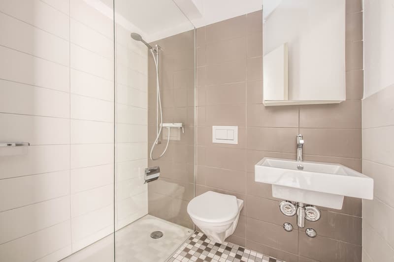 modern bathroom with shower, toilet, sink, and tiled walls