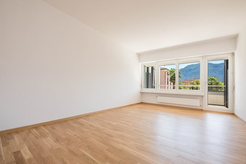 empty room, wooden floor, white walls, large windows with balcony, mountain view