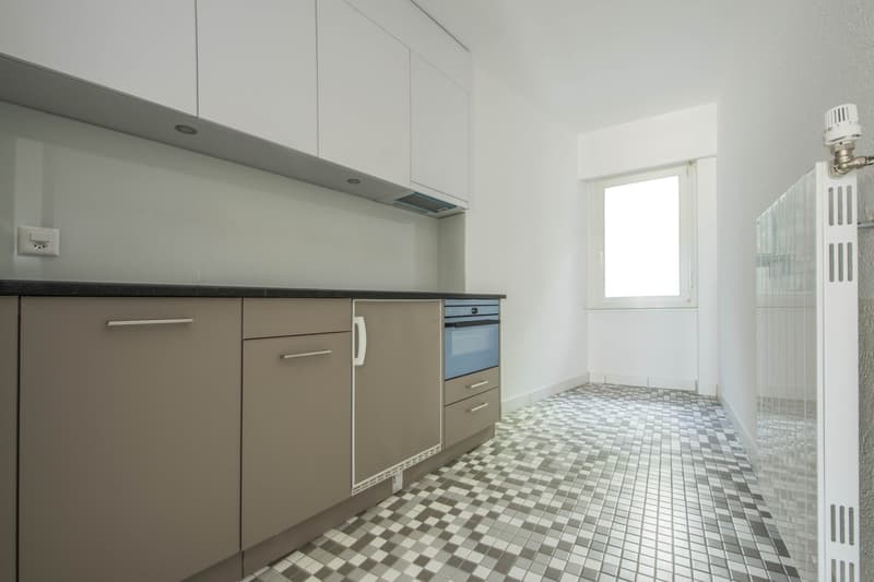 modern kitchen with white cabinets, gray tiled floor, built-in oven, dishwasher, power outlet